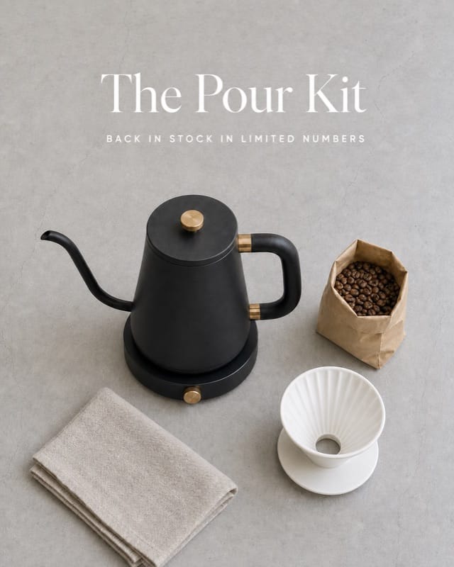 Overhead flat lay of the kettle with coffee beans, a ceramic dripper and linen cloth